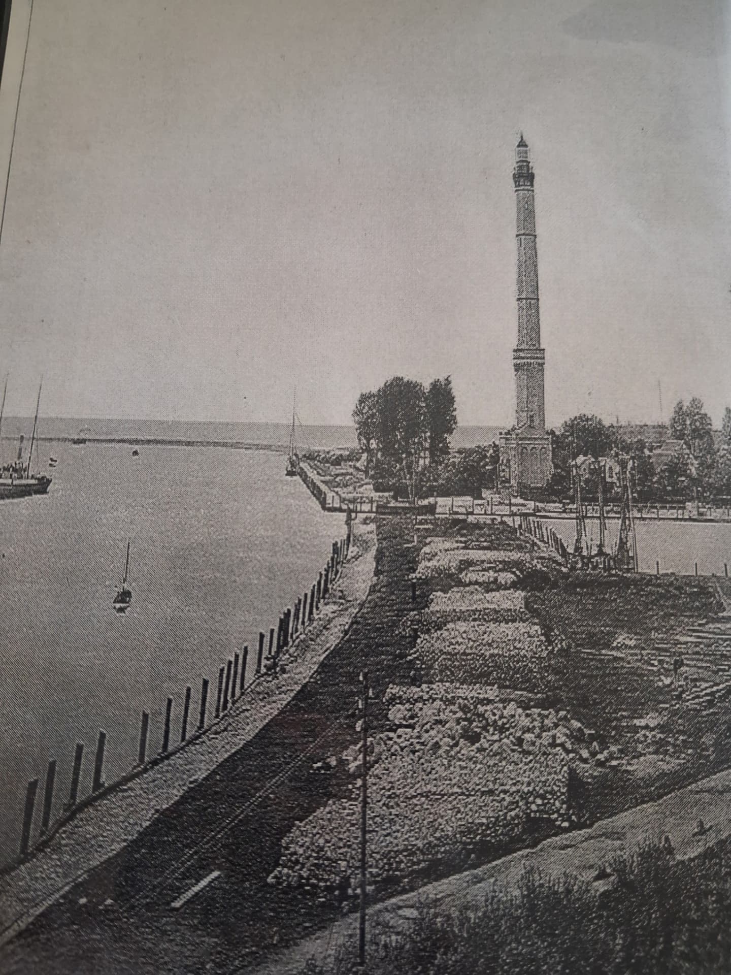 Vintage coastal lighthouse and calm water under a grey sky